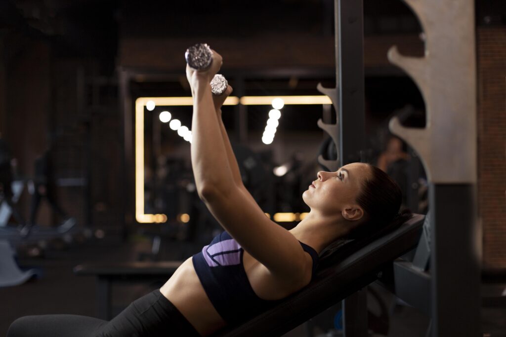 medium shot woman lifting dumbbells